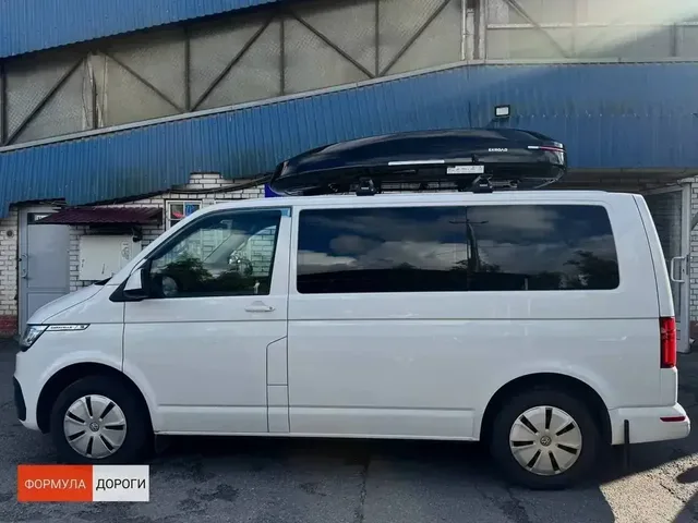 Бокс на крышу ENROAD Nomadix Pro XXL 600-E для Volkswagen Multivan T6, цвет «Чёрный» — передний ракурс автомобиля слева и пропорции автобокса
